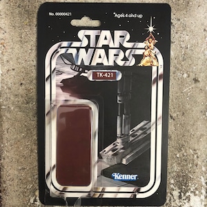 May include: Vintage Star Wars action figure on a black and white card. The card features the Star Wars logo, the text "TK-421", and the Kenner logo. The packaging is for ages 4 and up.