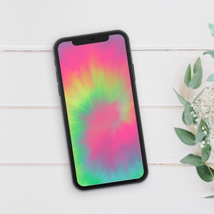 May include: A black smartphone with a tie-dye pattern on the screen. The phone is lying on a white wooden surface.