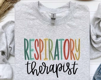 May include: A gray sweatshirt with the text "RESPIRATORY therapist" in colorful rainbow letters. The text is in a retro style font.