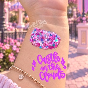 May include: A swatch of multi-colored chunky glitter in shades of pink, purple, and blue, featuring small heart and mouse-ear shapes. Below the glitter, the text "Castle in the Clouds" is written in a bright purple, cursive, handwritten-style font.
