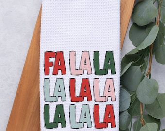 May include: White kitchen towel with the words "Fa La La La La La La La" printed in red, green, pink, and blue.