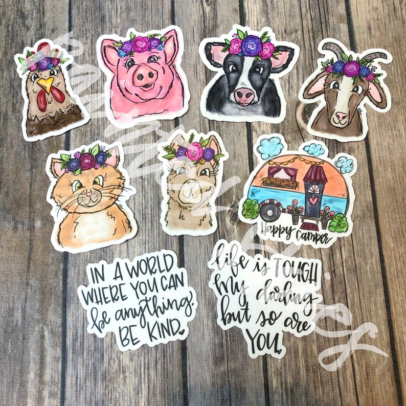 May include: Set of nine watercolor stickers featuring various animals wearing flower crowns. The animals include a pig, cow, goat, cat, llama, chicken, and a camper van. The stickers also include two inspirational quotes: "In a world where you can be anything, be kind." and "Life is tough, my darling, but so are you."