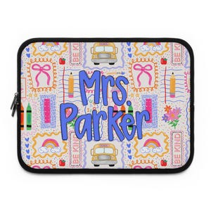 May include: A white laptop sleeve with a black zipper and trim. The sleeve features a colorful pattern of school-themed illustrations, including pencils, crayons, rainbows, and school buses. The name "Mrs. Parker" is prominently displayed in blue.