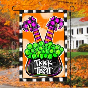 May include: A Halloween garden flag with a black cauldron filled with green candy and two witch legs sticking out of the top. The cauldron has the text "Trick or Treat" on the front. The flag has a black and white checkered border.