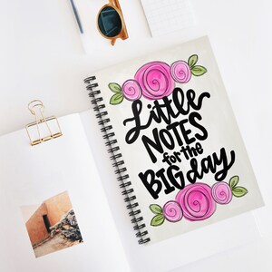 May include: A white spiral notebook with a pink floral design and the text "little notes for the big day".