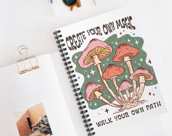 May include: Spiral-bound notebook with a colorful mushroom illustration. The design features pink and orange mushrooms with the text "CREATE YOUR OWN MAGIC WALK YOUR OWN PATH" in a retro font. The notebook is open, revealing blank pages.