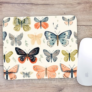 May include: A white mouse pad with a repeating pattern of colorful butterflies. The butterflies are painted in shades of blue, green, orange, and pink.