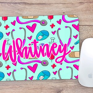 May include: A light blue mouse pad with a pattern of pink hearts, stethoscopes, bandages, and medical symbols. The name "Whitney" is written in pink cursive letters in the center of the mouse pad.