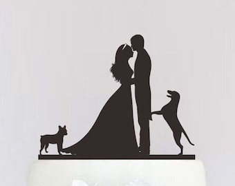 May include: A white wedding cake with black ribbon accents and a topper featuring a bride and groom silhouette with two dogs.