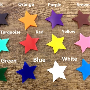 Op de afbeelding: Een set van 12 stervormige knutselbenodigdheden in verschillende kleuren, waaronder zwart, oranje, paars, bruin, turquoise, rood, geel, roze, groen, blauw, wit en aqua.