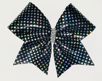 May include: A black cheer bow with iridescent white polka dots and a rhinestone center.