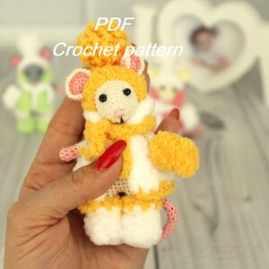 Peut inclure: Une souris au crochet portant un manteau jaune et blanc avec un nez rose et un bonnet blanc à pompon. La souris tient une moufle jaune au crochet. Le texte "PDF Crochet pattern" est visible au-dessus de la souris.