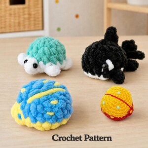 May include: Four crocheted animal toys: a turtle with a teal shell, a black and white orca, a blue and yellow fish, and a yellow ball with red accents. The words "Crochet Pattern" are printed at the bottom.