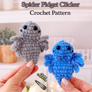 May include: Two crocheted spider fidget clickers, one gray and one blue, with black button eyes and eight legs. The image includes the text "Spider Fidget Clicker Crochet Pattern" and a snap hair clip.