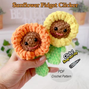 Puede incluir: Dos juguetes fidget de girasol hechos a mano, uno naranja y otro amarillo, con centros marrones y caras sonrientes. Los girasoles tienen tallos y hojas verdes. El texto de la imagen dice "Sunflower Fidget Clicker" y "Clicky! Snap hair clip".