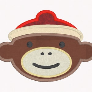 May include: A brown monkey face with a white and brown smile and black eyes. The monkey is wearing a red and white hat.