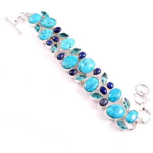 May include: A silver bracelet with turquoise, blue, and green gemstones. The bracelet has a lobster clasp closure.