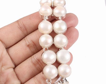 May include: A white pearl bracelet with a silver clasp. The bracelet is made of round pearls that are strung together in a double row.