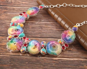 Puede incluir: Un collar colorido hecho de rodajas de ágata arcoíris y conectores de plata. El collar presenta una variedad de colores, incluyendo rojo, naranja, amarillo, verde, azul y morado. Las rodajas de ágata son todas de diferentes formas y tamaños, y están dispuestas en un patrón aleatorio. El collar es una pieza de joyería hermosa y única.