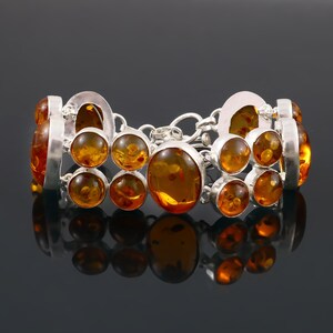May include: A silver bracelet featuring amber gemstones. The bracelet has a chain link design and is decorated with multiple round and oval-shaped amber stones.