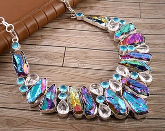 Puede incluir: Un collar de plata con piedras de cristal iridiscentes de colores arcoíris y piedras de acento transparentes y azules.