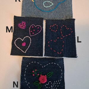 Puede incluir: Cuatro parches de mezclilla con dise&ntilde;os bordados. Uno presenta un p&aacute;jaro azul, otro tiene tres corazones y un tercero un coraz&oacute;n con una rosa y hojas. El cuarto parche tiene tres corazones.