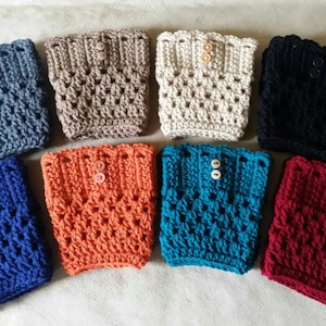 May include: Eight crocheted boot cuffs in various colors, including gray, beige, cream, black, orange, teal, and burgundy. Each cuff features a button closure.