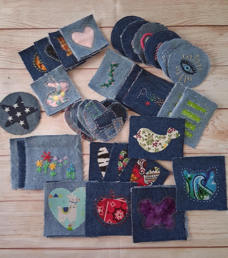 May include: A collection of denim patches with various designs, including hearts, stars, flowers, and a bird. Some patches feature embroidery, while others have fabric appliqu&eacute;s. The patches are in various shapes and sizes, perfect for crafting and DIY projects.