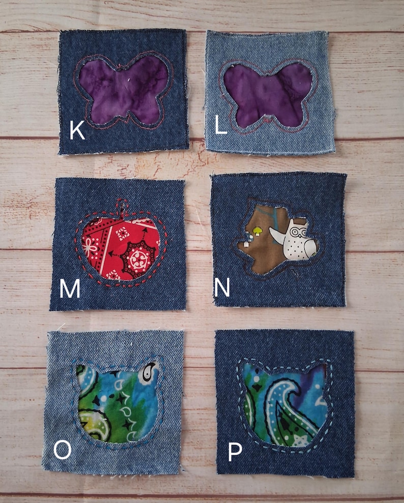 May include: Six denim fabric squares with various appliqued designs. The designs include a purple butterfly, a red apple, a brown bear with an owl, and two cat faces with paisley patterns. Each square is outlined with white stitching.