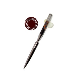 May include: A silver letter opener with a black and orange wood handle. The handle has a decorative pattern.