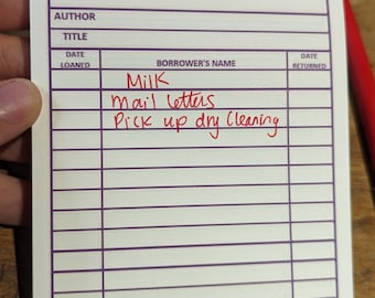 May include: A white card with purple lines and the text "KNOX ACCESSORIES CANADA" at the top. The card has columns labeled "AUTHOR", "TITLE", "DATE LOANED", "BORROWER'S NAME", and "DATE RETURNED". The borrower's name is written in red ink as "Milk" and the title is written in red ink as "mail letters Pick up dry cleaning".