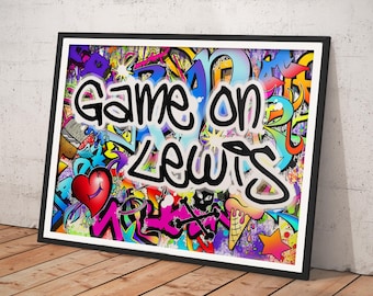 May include: A framed rectangular wall art piece featuring vibrant graffiti-style artwork with a colorful background of abstract shapes, a red heart, and an ice cream cone. The text "Game on Lewis" is written in bold black letters across the center.