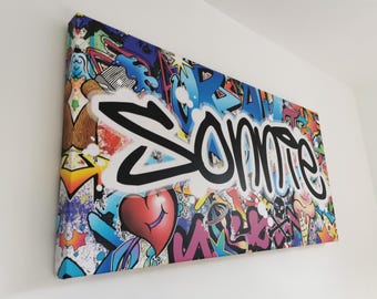May include: A rectangular canvas wall art piece featuring a vibrant graffiti-style collage with various symbols including a red heart, a skull, and an ice cream cone. The word "Somie" is written in large, bold black script across the center.