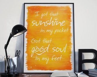 May include: A framed print with a yellow and orange watercolor background. The text on the print reads "I got that sunshine in my pocket Got that good soul in my feet".