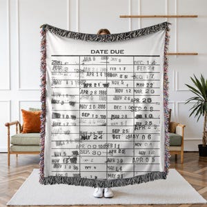 May include: A white woven tapestry with a black and white design of a library card with the text "DATE DUE" and a grid of dates.