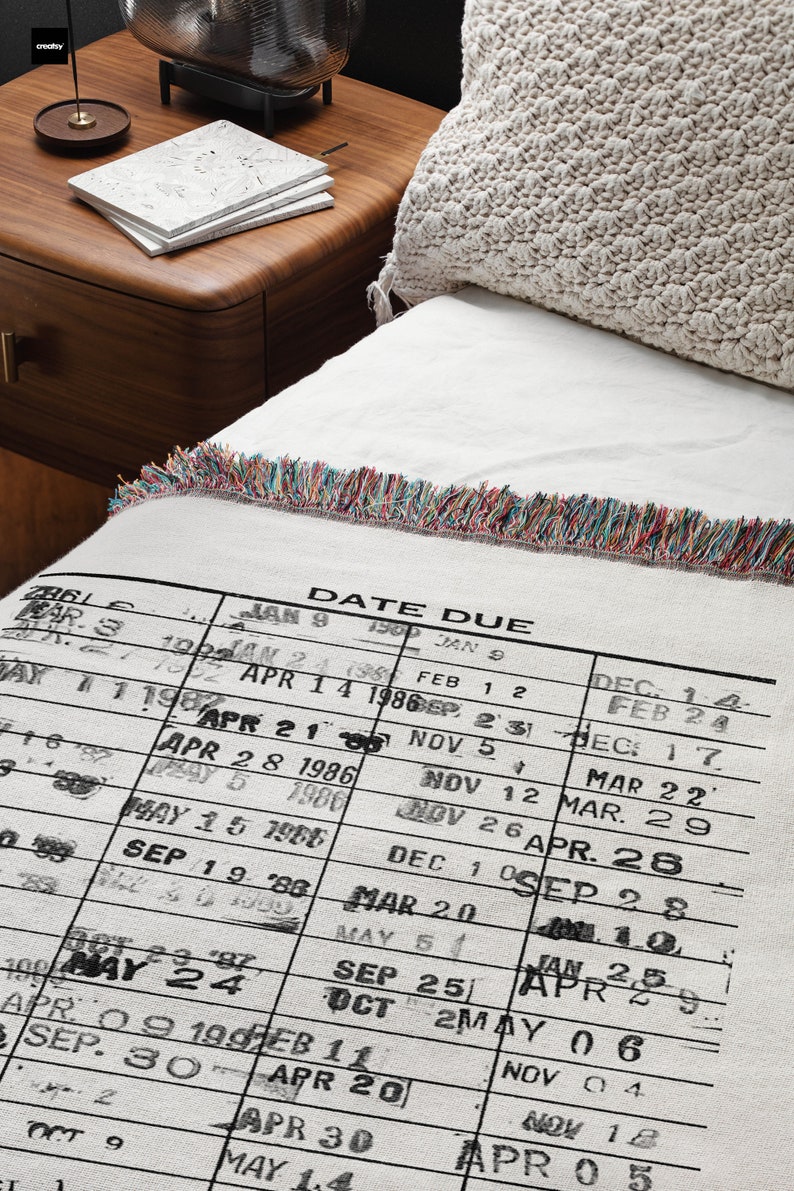 May include: A white woven throw blanket with a black and white printed calendar design. The calendar shows dates and months from January 1986 to May 1987. The blanket has a colorful fringe border.