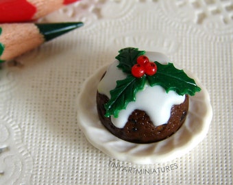 May include: A miniature Christmas pudding with white icing and a green holly sprig with red berries on top, sitting on a white plate.