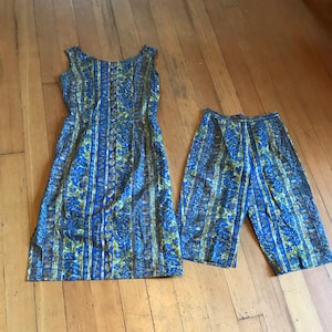 May include: A blue and green patterned dress and matching trousers. The dress is sleeveless and has a scoop neck. The trousers are capri length.