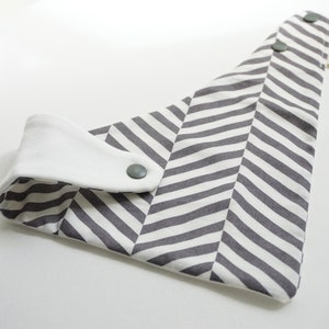 May include: A gray and white chevron patterned bib with a white cotton snap closure and two gray snaps.