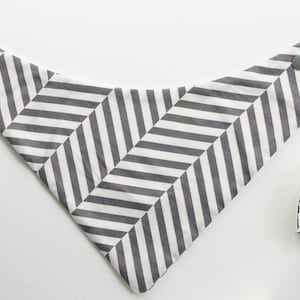 May include: A white and gray chevron patterned bandana with two snap closures. The bandana has the text "Follow Your Dreams" on a white heart-shaped tag.