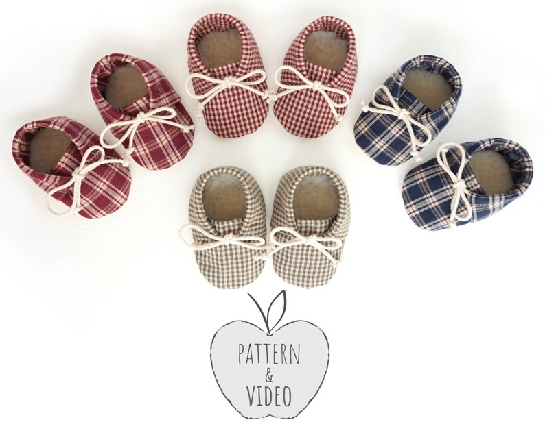 May include: Six pairs of baby booties in red, blue, and beige plaid fabric with white ties. The booties are arranged in a circle on a white background. The text "PATTERN & VIDEO" is written in black on a gray apple shape.