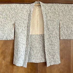 Könnte beinhalten: Ein weiß-graues Kimono mit einem hellgrauen Futter. Das Kimono ist vorne offen und hat lange Ärmel.