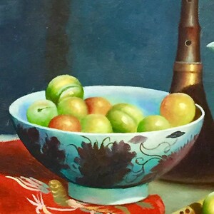 May include: A blue and white porcelain bowl filled with green and yellow fruit. The bowl is sitting on a red cloth with a wooden flute and a brown musical instrument.