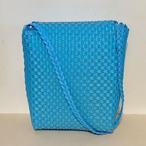 May include: A light blue woven plastic tote bag with a braided strap.