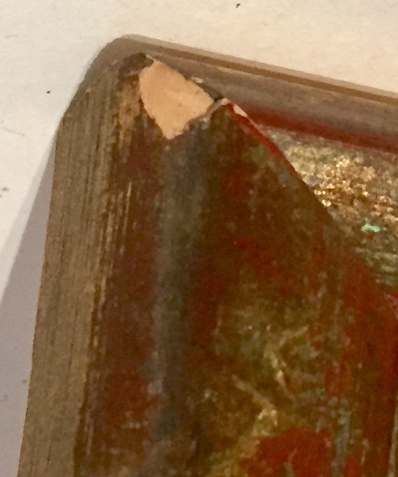 May include: Close-up of a wooden frame with a chipped corner. The frame is painted in shades of red, brown, and gold. The frame is likely for a painting or artwork.