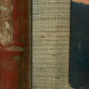 May include: Close-up of a red, brown, and gold wooden frame with a beige fabric lining. The fabric has a woven texture.