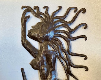 May include: A brown metal sculpture of a mermaid with long, flowing hair and a tail with scales. The mermaid is holding a staff in her right hand and is looking upwards.