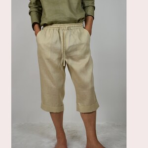 May include: Beige linen trousers with a drawstring waist and cuffed hems.
