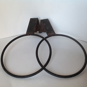 May include: Two rusty metal rings with a hook on each side. The rings are connected together and are likely used for hanging items.