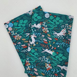 May include: Three teal blue fabric napkins with a white bunny rabbit and floral pattern.